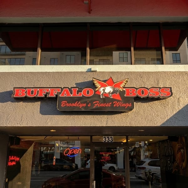 The Buffalo Boss restaurant storefront with a red and black sign, and an "Open" neon sign.